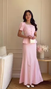 A full-length view of an elegant pink two-piece peplum top and mermaid skirt set.