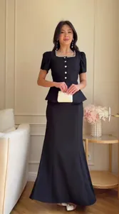 Elegant woman wearing black short-sleeve peplum top and mermaid maxi skirt set in room