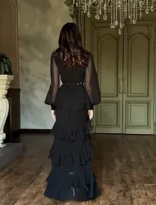 Back view detail of an elegant black long-sleeved tiered maxi dress with sheer sleeves.
