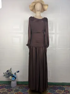 Detailed view of an elegant brown pleated maxi dress with long sleeves on a mannequin.