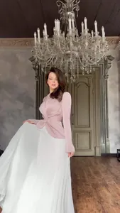 Elegante tweekleurige jurk met lange mouwen, roze top en een witte geplooide rok.