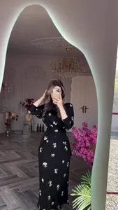 Élégante robe midi noire à imprimé floral blanc présentée dans un cadre élégant
