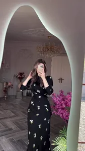 Selfie miroir d'une femme portant une robe midi noire à fleurs dans une chambre