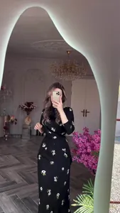 Robe noire élégante à manches longues avec imprimé floral blanc pour un look d'été chic.