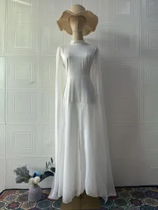 Elegant white long-sleeve maxi dress with cape sleeves on a mannequin for Fall 2025