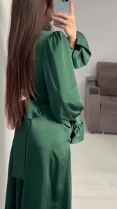 Detail view of an emerald green satin dress showing bubble sleeves and waist design.