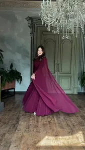 Elegant burgundy long-sleeved maxi dress with flowing skirt in a luxury interior.