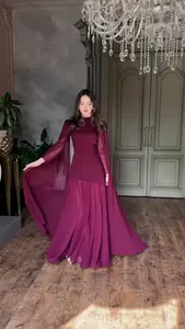Elegant burgundy long sleeve maxi dress with cape sleeves in a luxury interior setting.