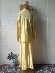 Back view of a yellow two-piece set featuring a loose long-sleeved shirt and long skirt.
