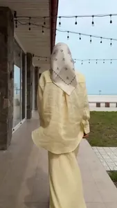 Elegant yellow long-sleeved linen shirt and skirt set back view on seaside terrace