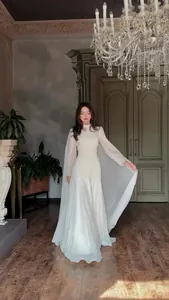 Elegant white floor-length evening gown with long cape sleeves for glamorous 2025 galas.