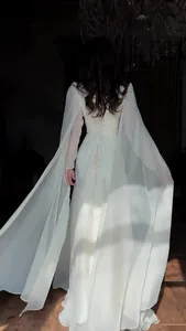 Back view of a graceful white maxi dress with flowing cape-like sleeves and lace-up back