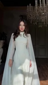 Elegant white long sleeve maxi dress featuring sheer cape detail for formal occasions.