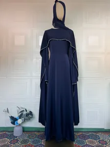 Detailansicht eines eleganten dunkelblauen Langarmkleids mit Perlenbesatz und Kopftuch