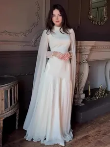 Elegant white long-sleeved maxi dress with dramatic cape sleeves for a formal autumn look