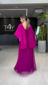 Achteraanzicht van elegante fuchsia maxi-jurk met cape-mouwen in modieuze showroom