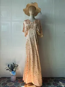 Vista a figura intera di un abito lungo in raso a fiori vintage su un manichino con cappello