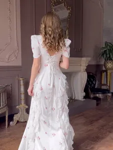 Elegant white floral maxi dress with short sleeves, ruffled details and a lace-up back design