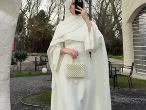 Detailansicht eines eleganten weißen Langarmkleides mit luxuriösem Perlenbesatz