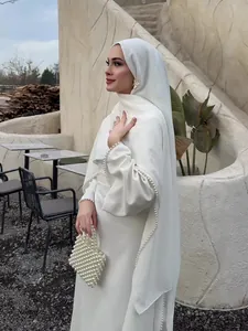 Elegantes weißes Langarmkleid mit exquisitem Perlenbesatz und passender Perltasche