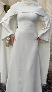 Detaillierte Ansicht des eleganten weißen Abendkleids mit Perlenbesatz und Umhang-Design