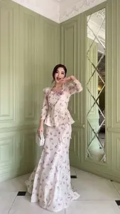 Elegante set con top peplo a fiori e gonna lunga indossato da una modella in una stanza