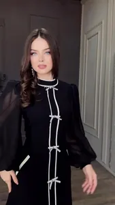 Détail des élégants nœuds blancs et du col montant sur cette robe noire raffinée