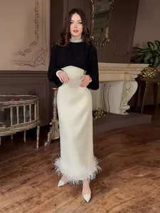 Elegante zwart-witte jurk met luxe parelafwerking en een stijlvolle veren zoom