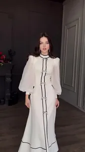 Élégante robe longue blanche ornée de nœuds noirs décoratifs et de manches lanterne