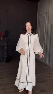 Longue robe blanche élégante avec des nœuds noirs et des manches bouffantes voilées.
