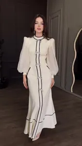 Robe longue de soirée blanche élégante avec bordure noire, nœuds et manches bouffantes.