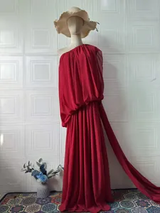 Detail view of elegant red one-shoulder pleated evening gown with flowing chiffon trail