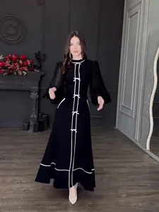 Robe longue élégante noir et blanc avec nœuds, col montant et manches transparentes.