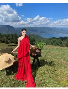 Elegant red one-shoulder pleated long dress with tail shown in a scenic outdoor setting