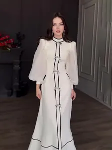 Robe longue blanche élégante avec bordure noire, nœuds argentés et manches bouffantes