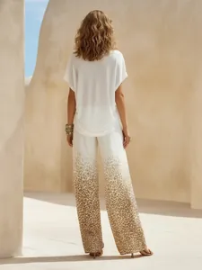 Vista posteriore di completo vacanze con top bianco e pantaloni leopardati sfumati.