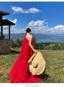Back view of an elegant red pleated maxi dress with a straw hat in mountain scenery