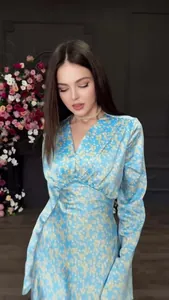 Detailaufnahme eines blauen V-Ausschnitt-Kleides mit gelben Blumenmustern.