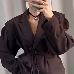 Detail shot of a dark brown V-neck blazer featuring a stylish tie-waist and puff sleeves