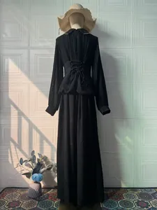 Back view detail of elegant black long-sleeved pleated maxi dress with corset waist.