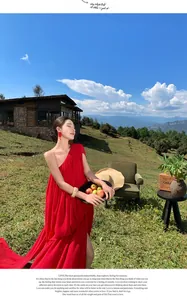 Elegant red one-shoulder pleated maxi dress with trailing hem for travel photography