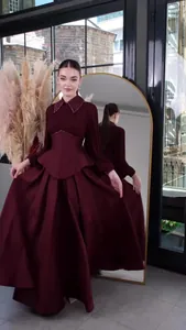 Elegant burgundy long-sleeved pleated maxi dress featuring a structured waist and collar