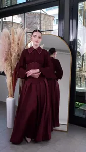 Detailed view of an elegant maroon long-sleeved dress with embellished collar and cinched waist.