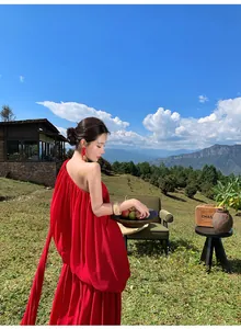 Elegant red one-shoulder pleated gown flowing gracefully in a mountain landscape setting