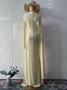 Elegante vestido largo crema de manga larga y un corte ajustado en un maniquí