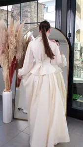 Elegant cream long-sleeved maxi dress with peplum waist and corset back detail