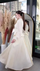 Elegant cream long-sleeved maxi dress with flowing skirt and cinched waist detail