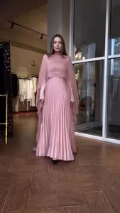 Elegante roze maxi-jurk met lange mouwen, plooien en een sierlijke cape-overlay.
