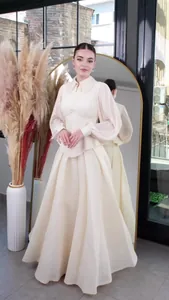 Elegant cream long-sleeved maxi dress with pleated details and flared skirt.