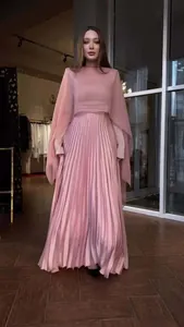 Detailweergave van een roze geplooide jurk met lange mouwen, taille en textuur van de stof